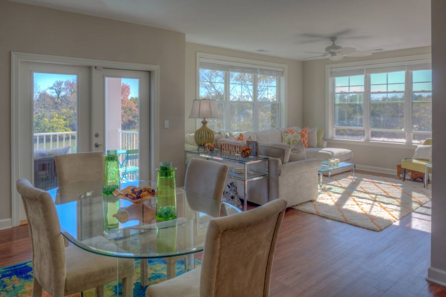 CovePointe apartment homes with Bright living and dining area with glass table, beige chairs, large windows, and cozy seating.