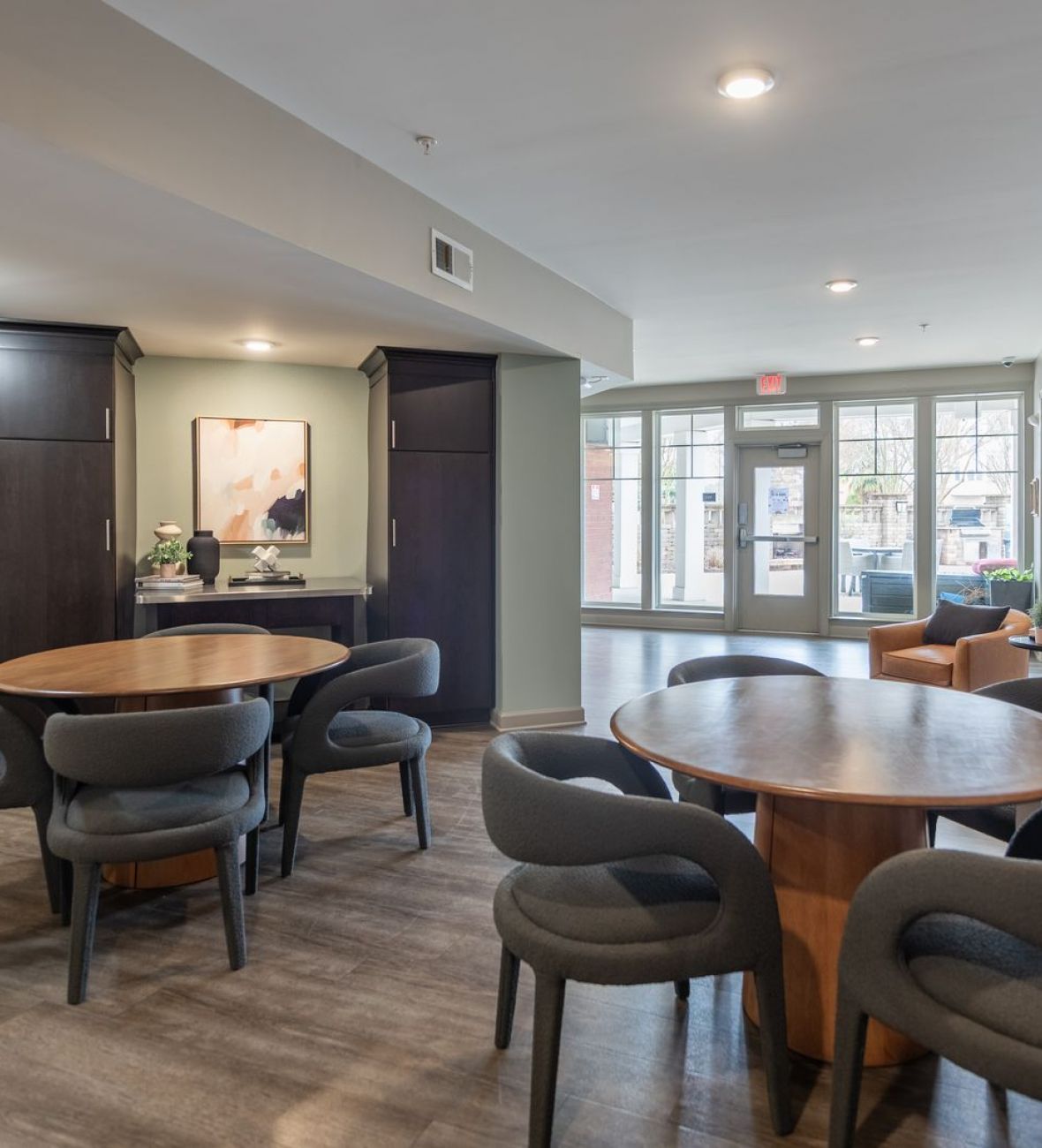 Attain on 5th apartment homes with A modern lounge area with round tables, gray chairs, large windows, and contemporary wall art.
