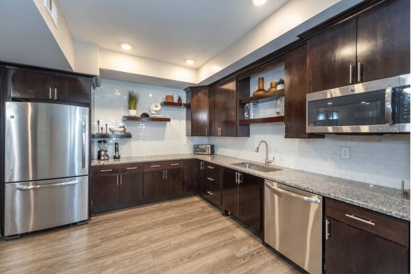 Modern kitchen with dark wood cabinets, stainless steel appliances, and white tile backsplash.