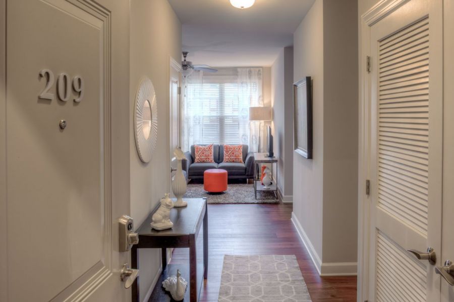 Attain on 5th apartment homes with An open apartment door reveals a hallway leading to a bright living room with modern decor.