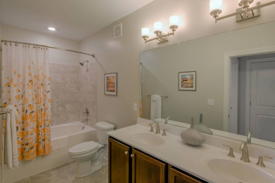 Attain on 5th apartment homes with Modern bathroom with a double sink vanity, large mirror, and a shower-tub combo with a floral curtain.