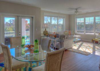 CovePointe apartment homes with Bright living and dining area with glass table, beige chairs, large windows, and cozy seating.