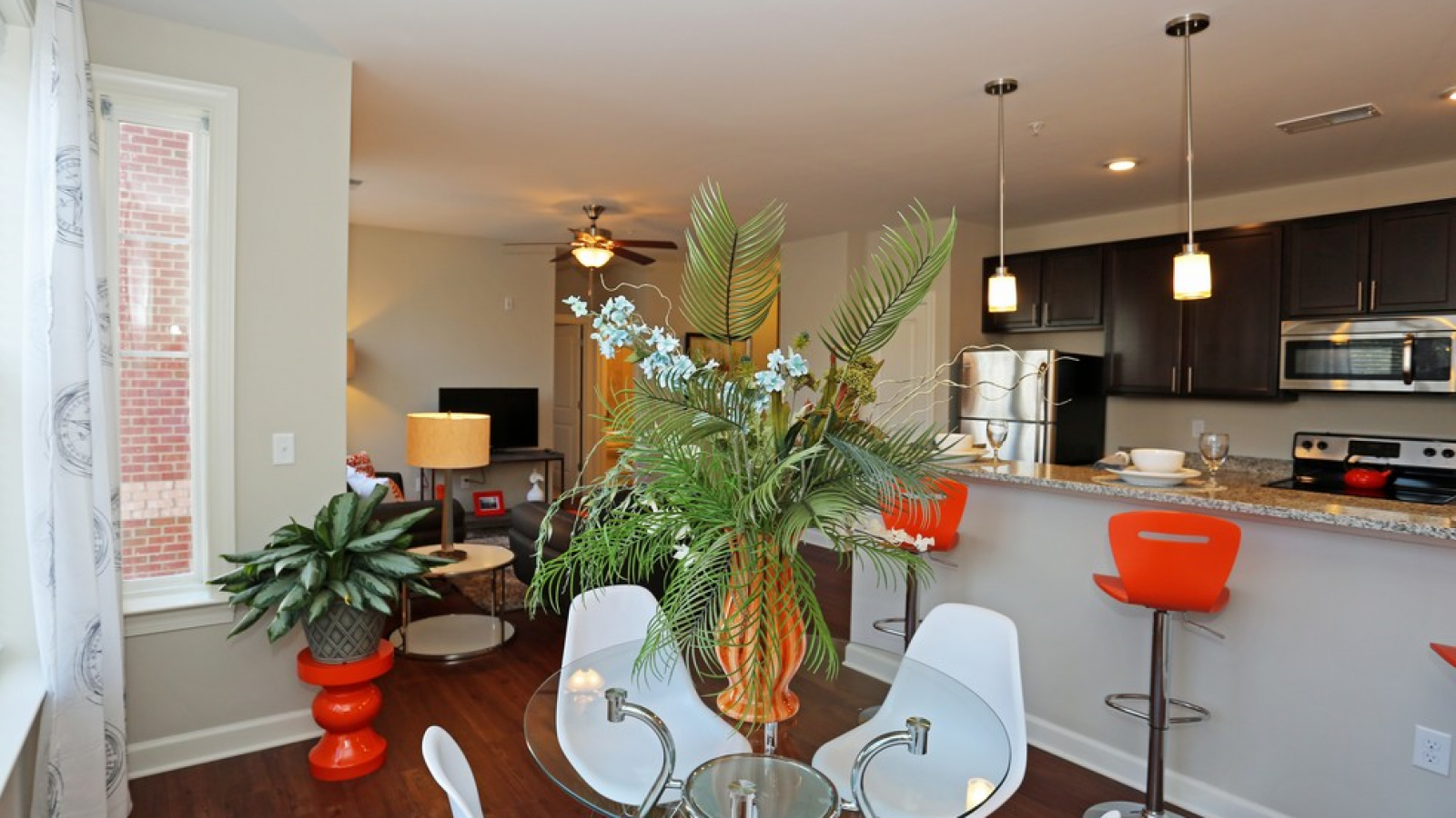 Modern kitchen and living area with white cabinets, stainless steel appliances, and a large island. Cozy seating area with a sofa and rug in the background. Bright and inviting atmosphere.